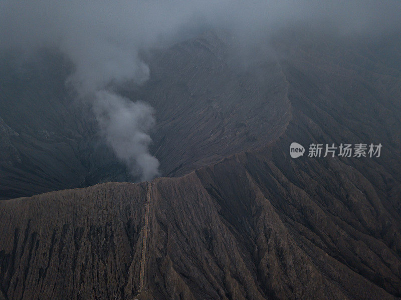 无人机鸟瞰图的Bromo火山口边缘与蒸汽在Bromo山国家公园在Cemoro Lawang村-东爪哇，印度尼西亚，亚洲。旅游目的地冒险的自然概念